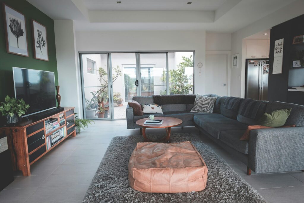 Interior of spacious living room with round coffee table placed on soft rug near comfortable sofa ad modern TV in cozy villa